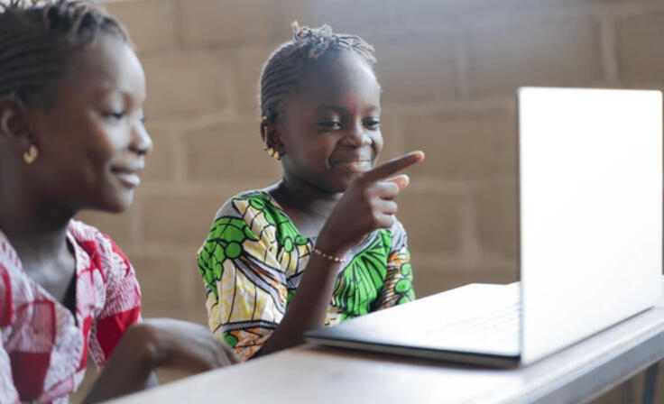 Ghanaian girls laughing and pointing at a laptop screen